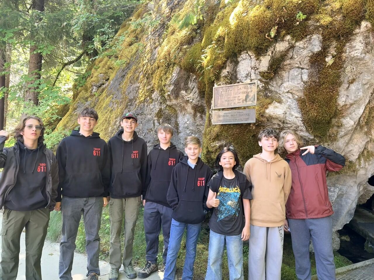 Scouts in troop hoodies at the mossy entrance of the Oregon Caves