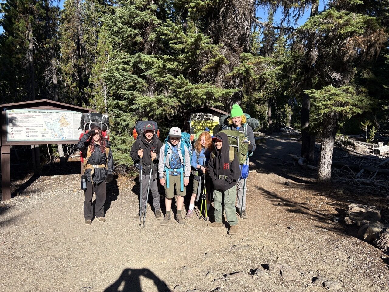 Scouts with full backpacks gathered at the wilderness trailhead sign
